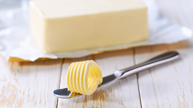 A block of butter with a knife beside it on table