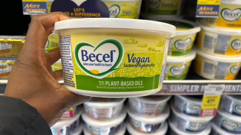 Hand holding a tub of Becel margarine in the grocery store