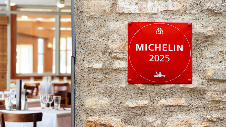 A red Michelin plaque is posted to a stone wall outside of a restaurant.