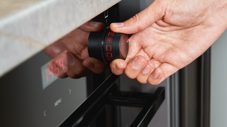 hand adjusting oven's temperature dial
