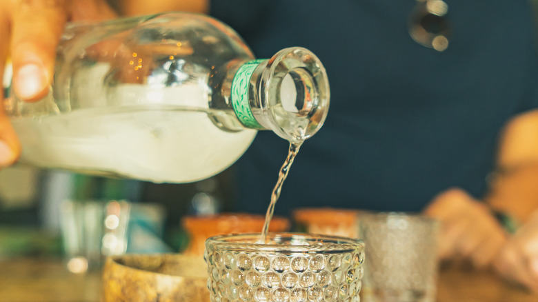 Mezcal is poured from a bottle into a glass