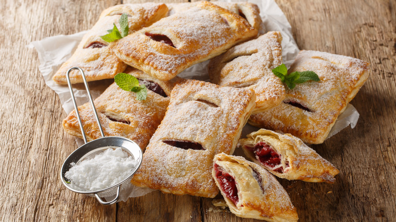 various fruit pies on a wooden board with powdered sugar