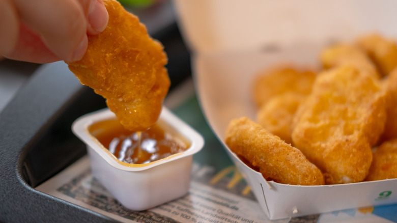 McDonald's chicken nugget being dipped into sauce