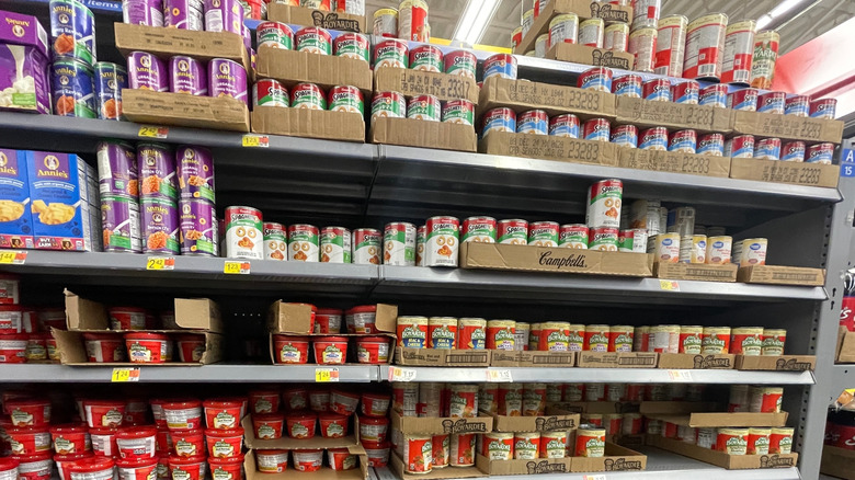 Grocery store canned pasta section with cans of Campbell's on the top two shelves and Chef Boyardee on the next two.