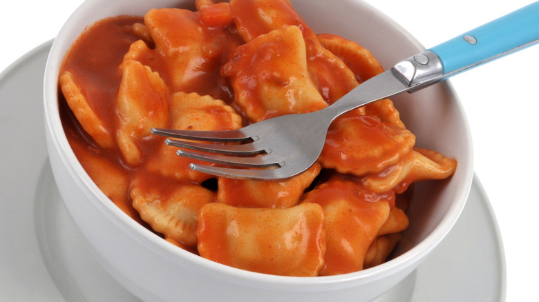 A white bowl of canned ravioli ready to enjoy.