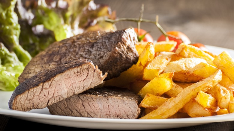 A well-done steak with fries.