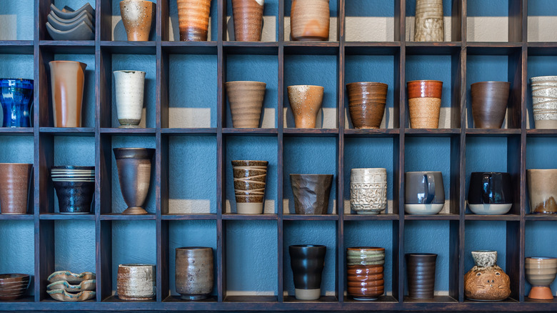 ceramic mugs on a gridwork of wooden shelves