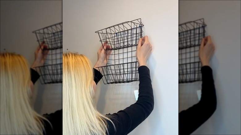 Blonde woman hanging up Dollar Tree wire basket hack.