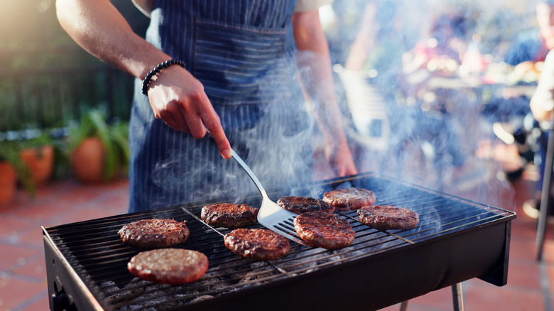 Man cooking beef burgers on an outdoor grill