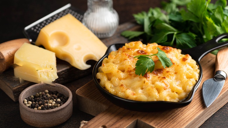 mac and cheese in small skillet with cheese and pepper next to it
