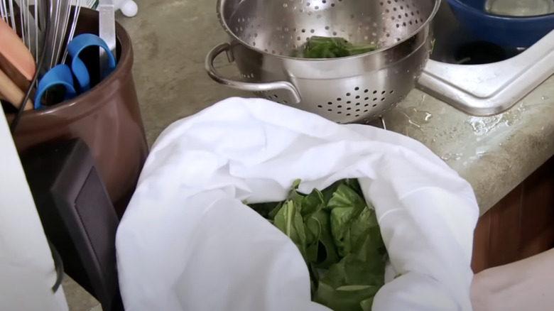 Pillowcase and colander with spinach next to kitchen tools