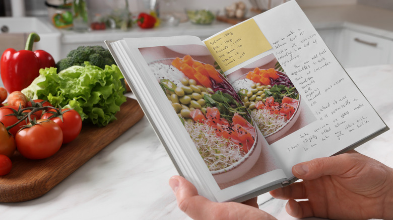 hands holding a book of handwritten recipes