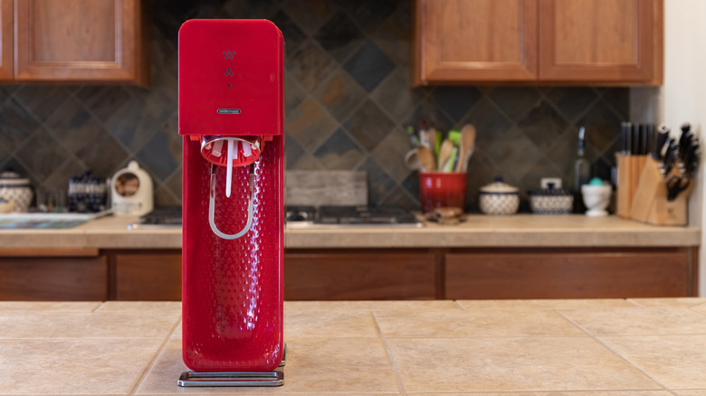 A red soda maker on a kitchen counter