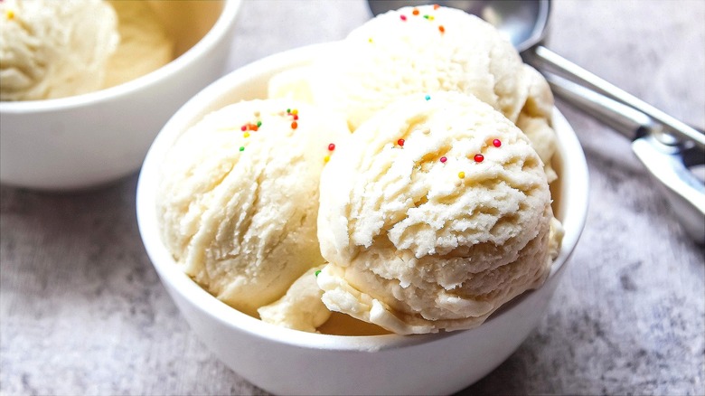 Three scoops of vanilla ice cream with rainbow sprinkles in a white bowl