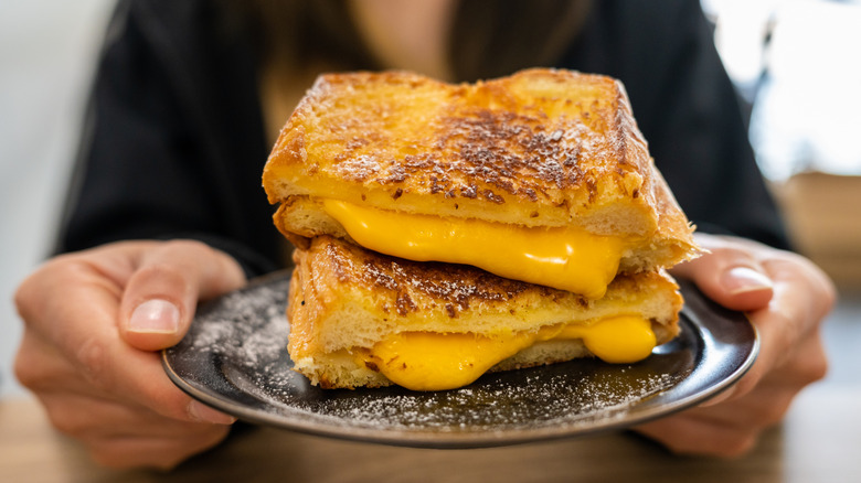 Person holding a plate with crispy grilled cheese