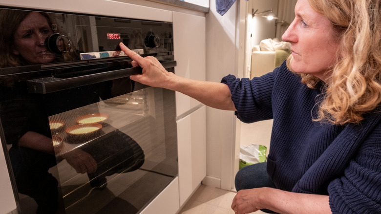 Woman making crème brûlée in oven