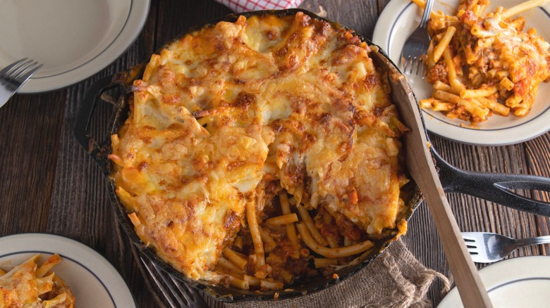 Lasagna baked in a cast iron pan and served on wooden table. Overhead view and ready to eat