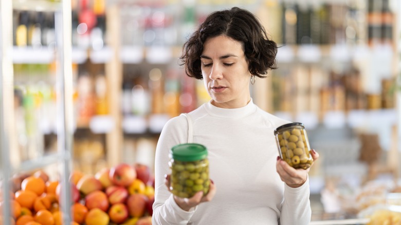 Woman choosing between jars of olives