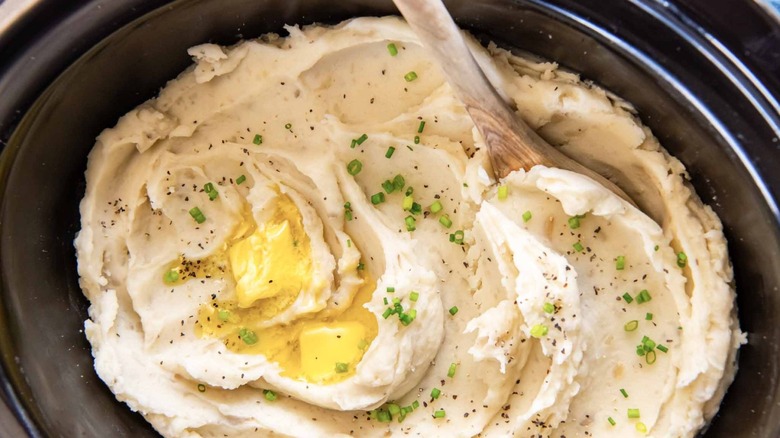 Mashed potatoes topped with butter and green onions in slow cooker