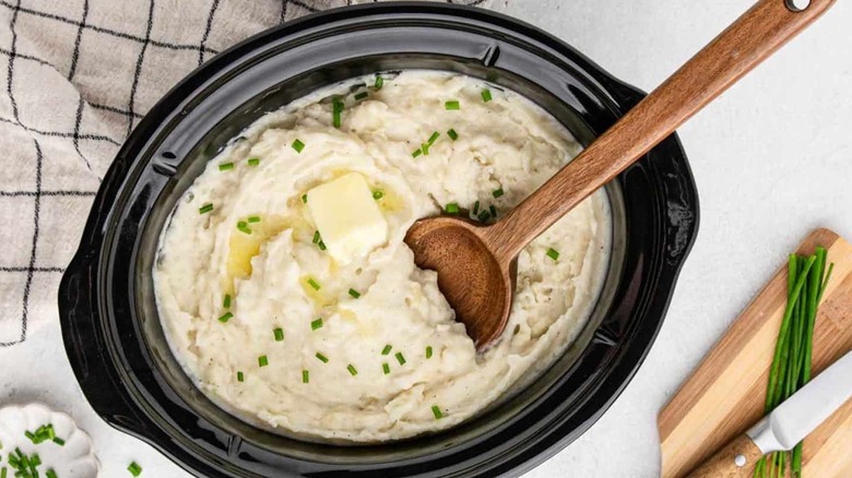 Mashed potatoes topped with butter and green onions in slow cooker