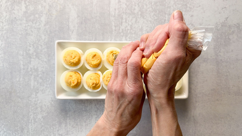 Filling hard boiled egg whites with deviled egg filling in pastry bag