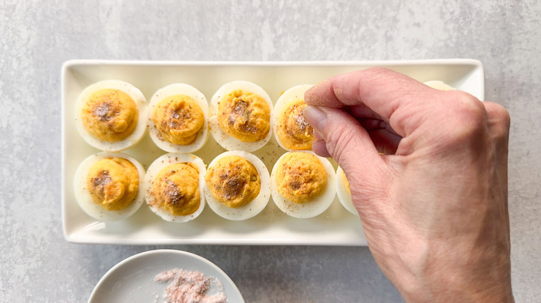 Sprinkling deviled eggs with ground nutmeg and sea salt