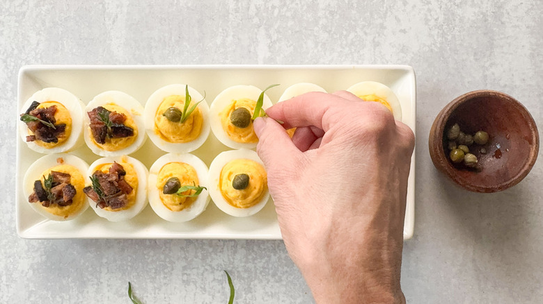 Garnishing deviled eggs with capers and tarragon