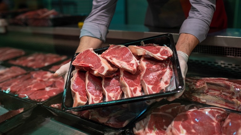 A butcher holding a tray of steaks