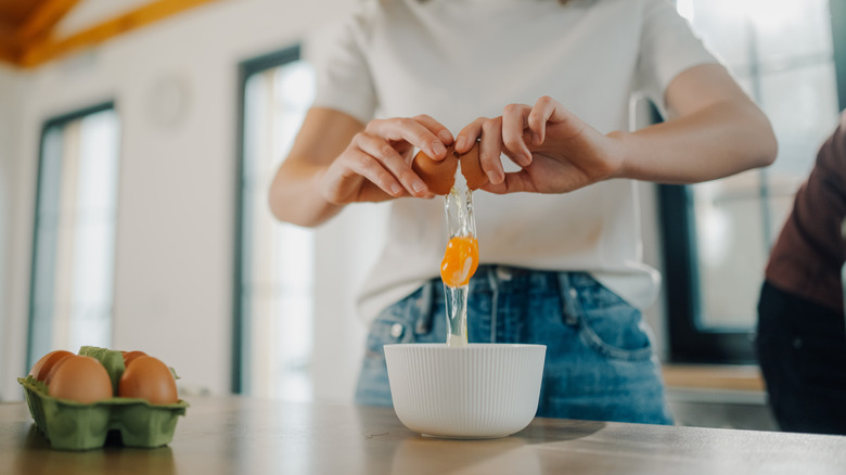 A person cracking an egg into a bowl
