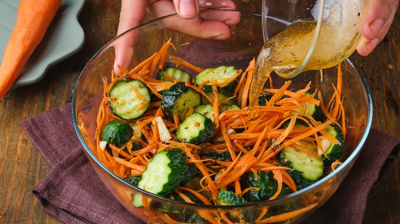Adding dressing to cucumber and carrot salad