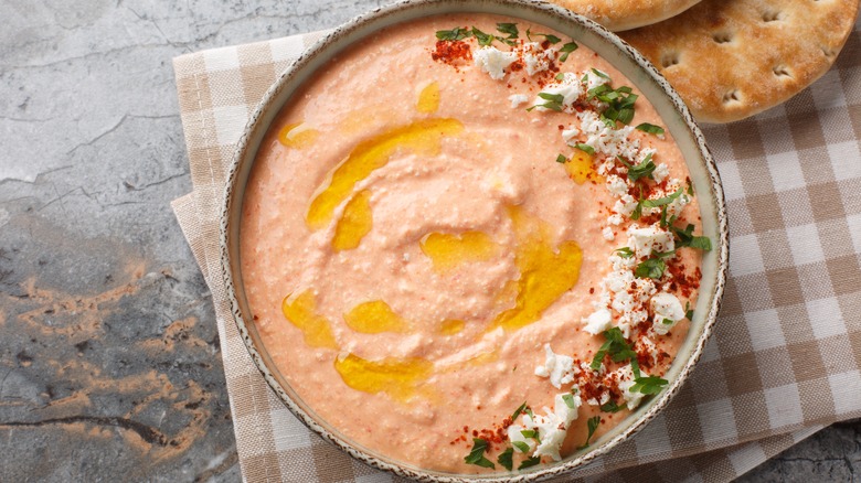 k spicy feta dip with creamy cheese, roasted red peppers, garlic, and chilli closeup on the bowl on the table.
