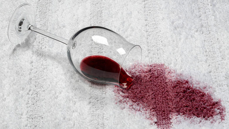 Red wine glass tipped over on white carpet