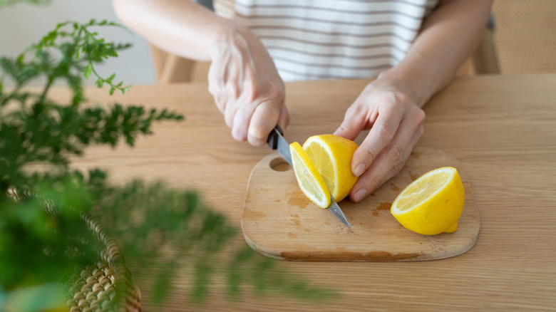 A closeup of a woman's hand cutting lemons