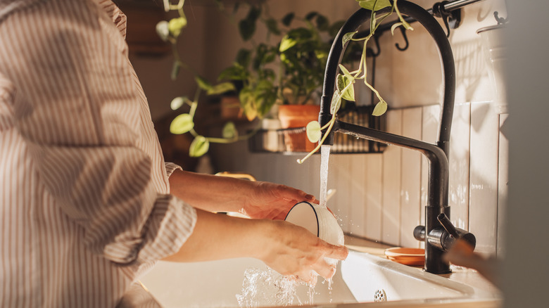 Person washing a bowl in the sink under running water