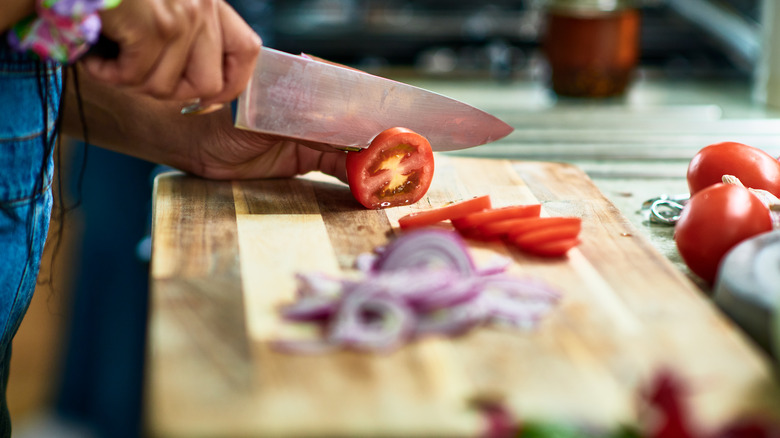 a cook cutting a tomato with a knife