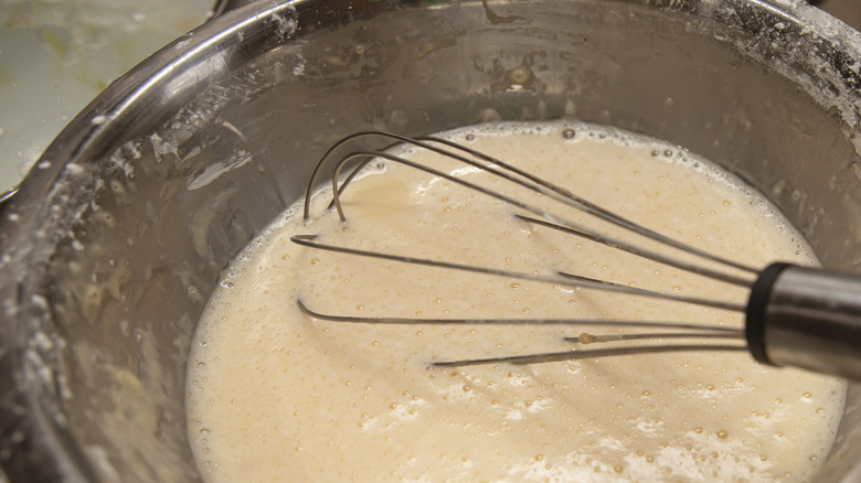Cooking whisk in a steel bowl full of batter.