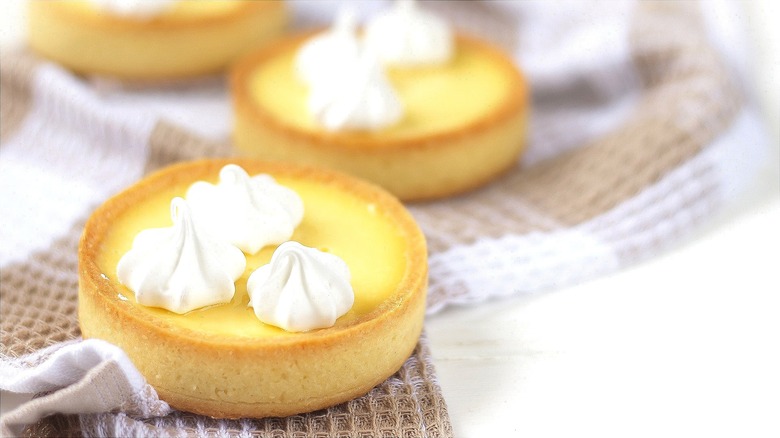Miniature lemon cream pies with whipped cream on a white and taupe checkered dish towel