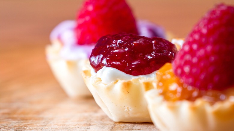 Close-up of phyllo shells filled with cream, fresh raspberries, and fruit filling