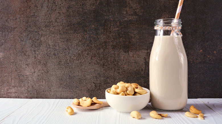 Glass of cashew milk next to bowl of cashews