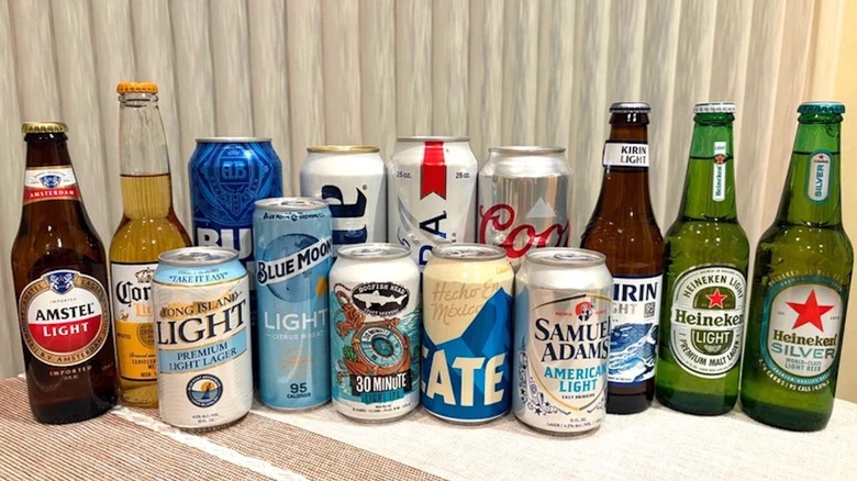 A grouping of various canned and bottled beer sitting on a table