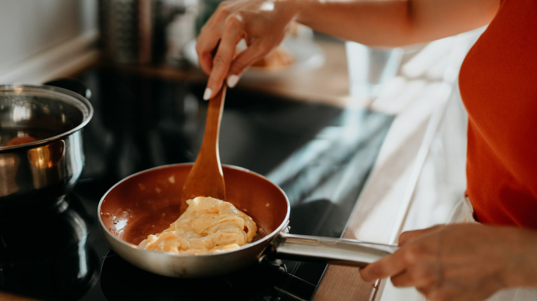Person cooking eggs in a pan on the stove