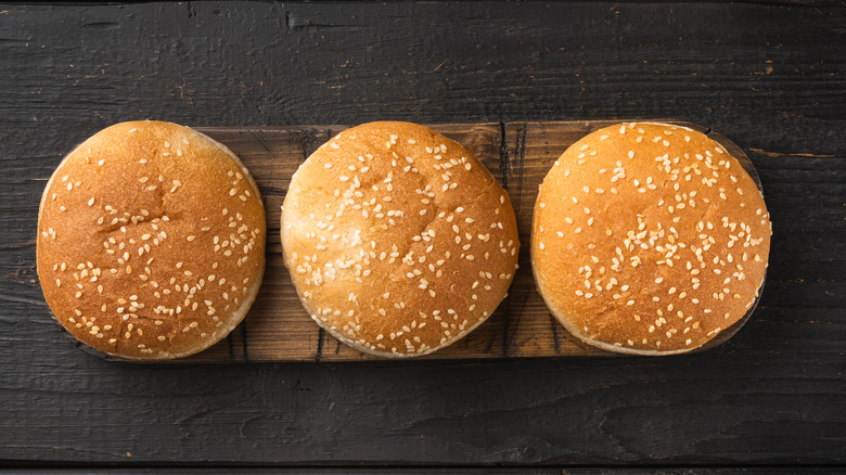 Burger buns with sesame seeds on a wooden board