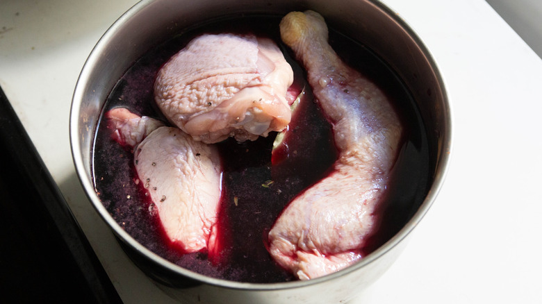 Chicken cooking in a pot with wine.