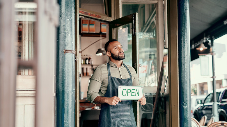 Man holding an open sign for his restaurant