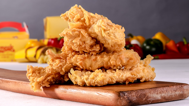 Fast food chicken tenders sitting on a wooden cutting board