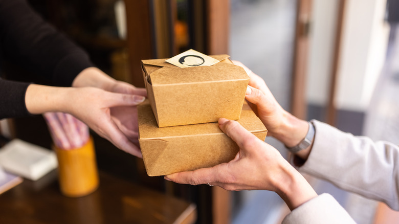 A fast food employee hands a customer multiple boxes of food