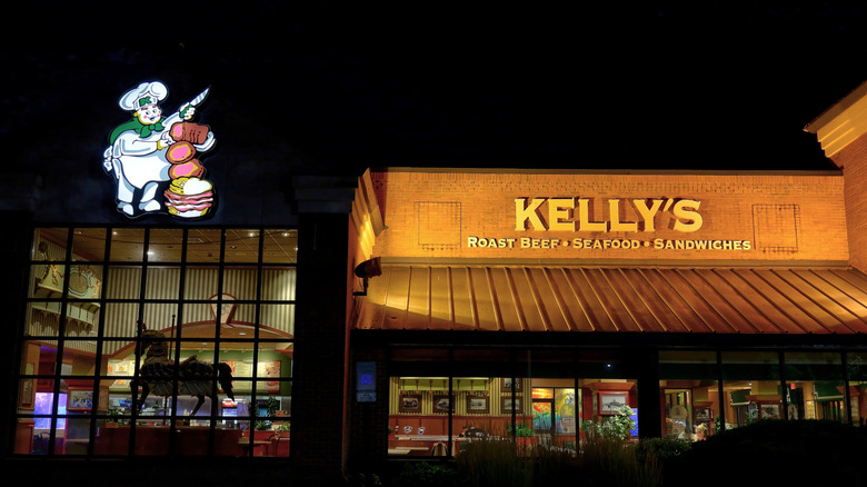 A Kelly's restaurant facade at night, with a lit-up cartoon of a chef carving meat.
