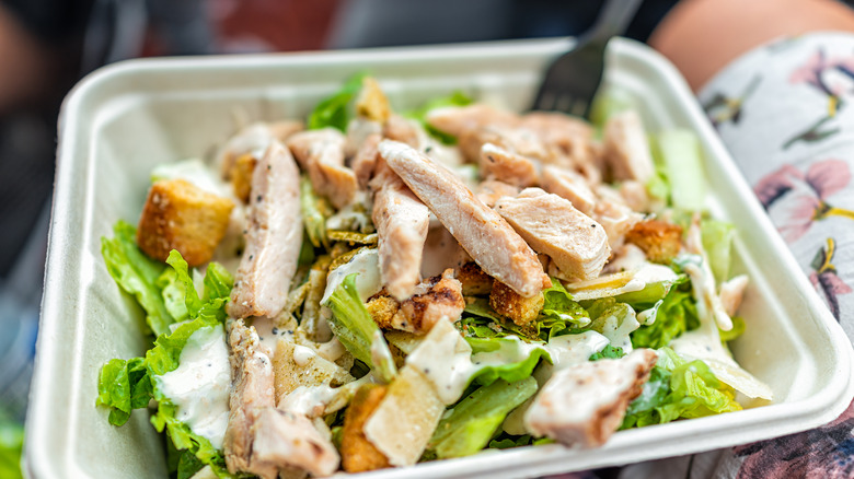 Chicken salad in a takeout container on a person's lap