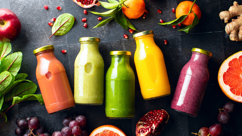 Various colors of smoothies in glass bottles.
