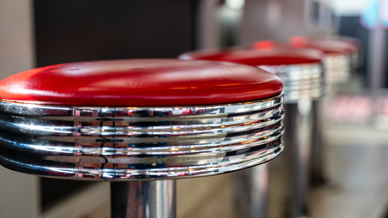 A row of the classic chrome-plated lunch counter stools with red cushioned tops